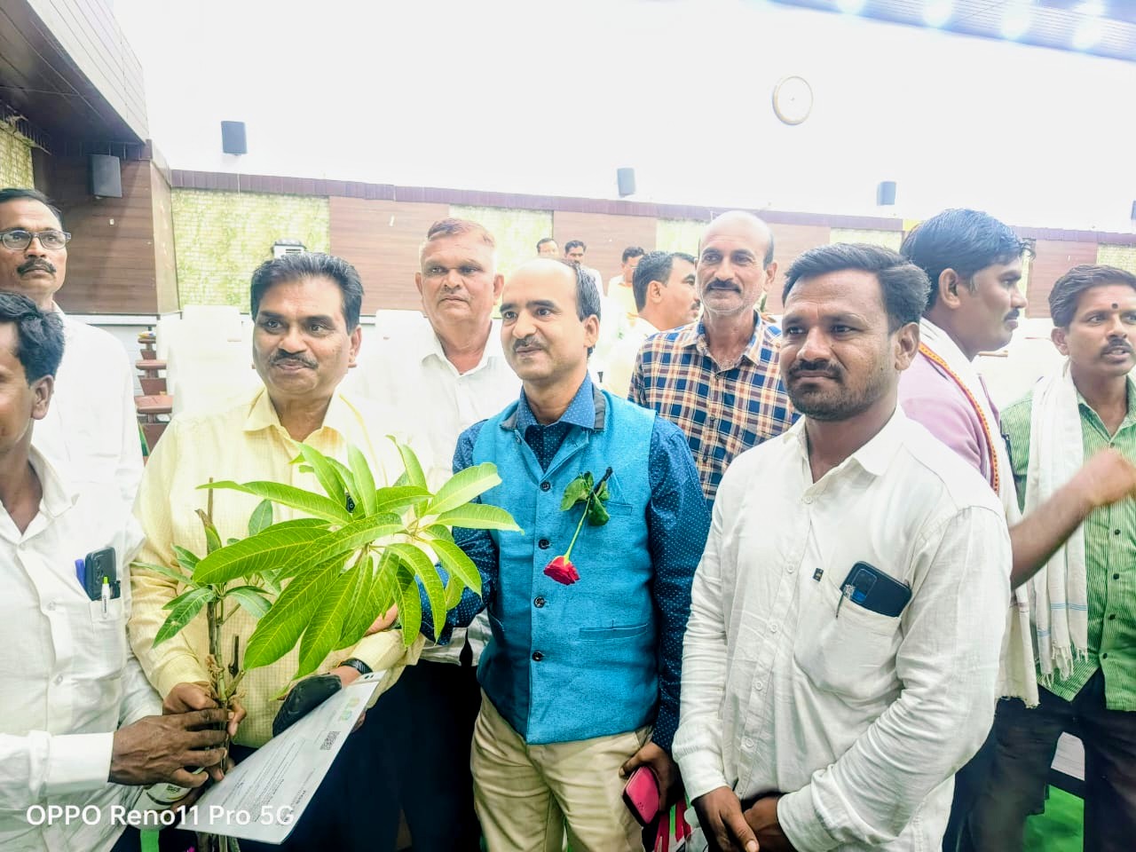 Group holding a mango sapling at a plantation event